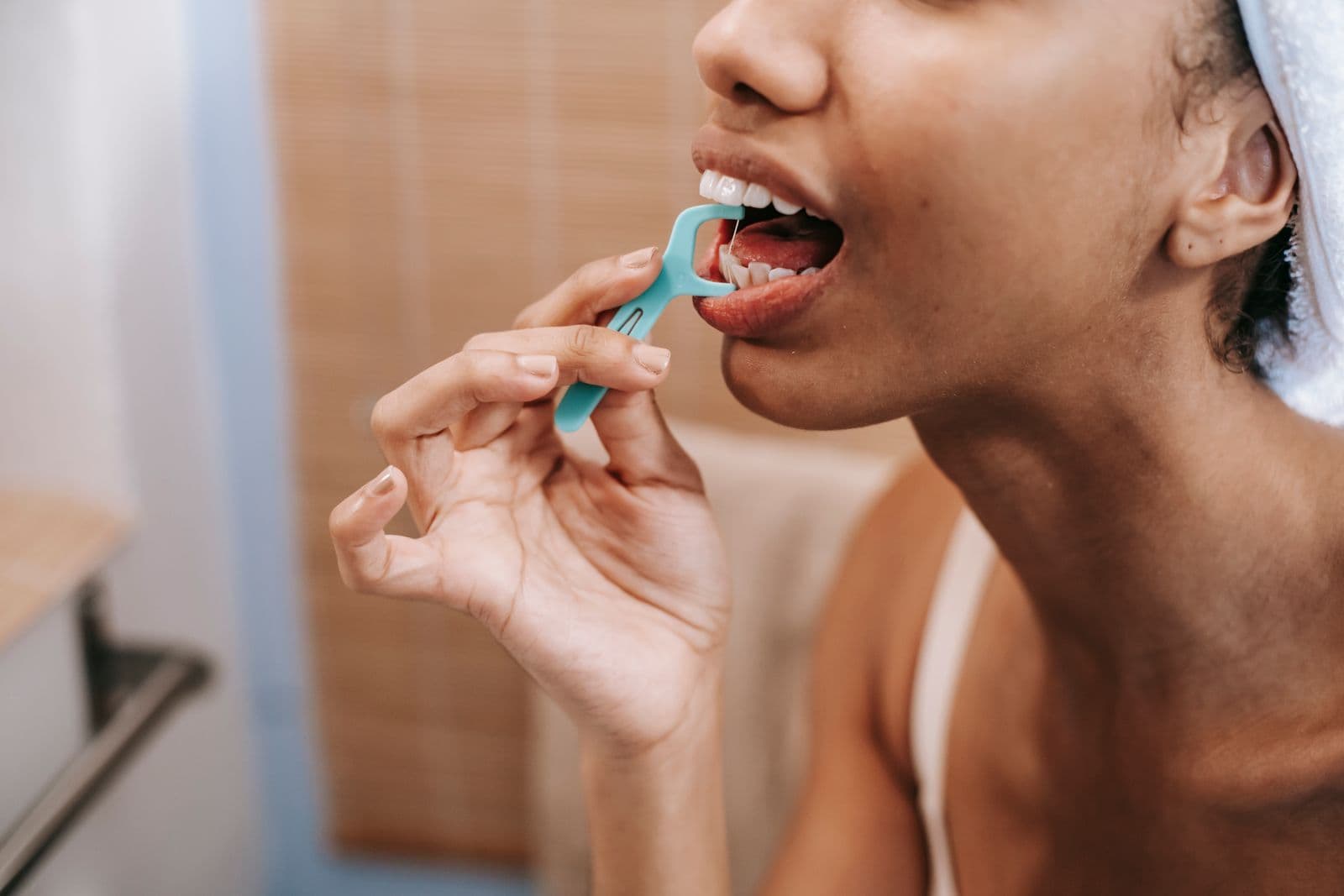 Woman flossing her teeth to help prevent gum bleeding at home