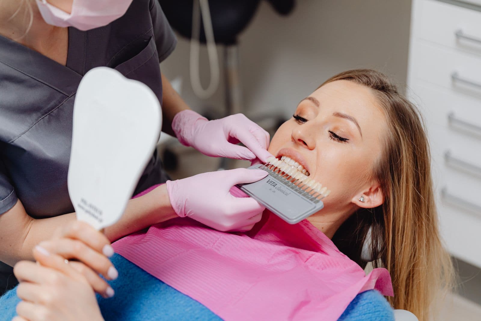 Dentist comparing tooth shades with a shade guide for a restoration