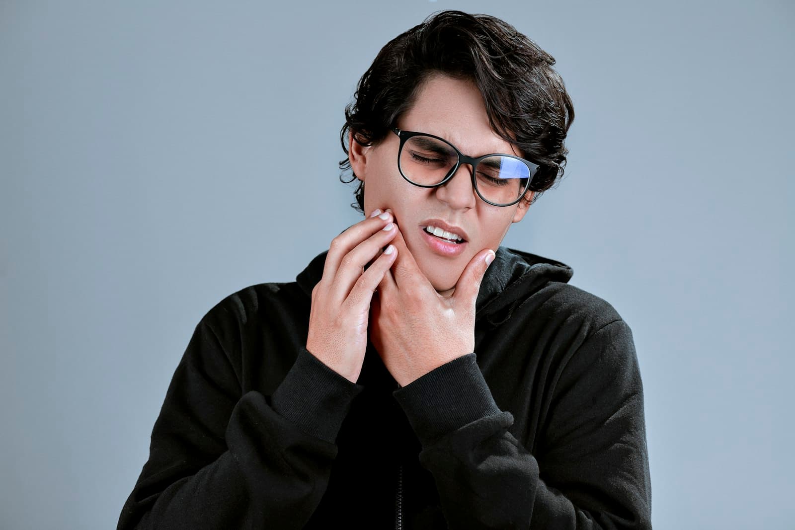 Person holding jaw in pain from possible tooth abscess symptoms