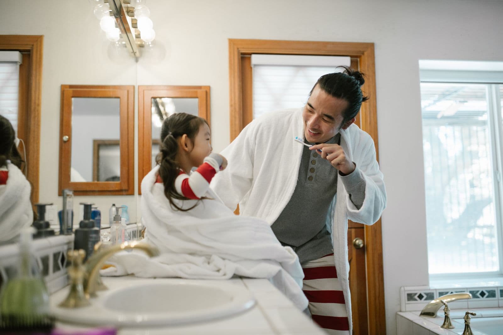 Parent helping child brush teeth before a first dental visit